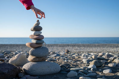 A hand puts stone on tower on beach, house by the sea. background for real estate advertising. 