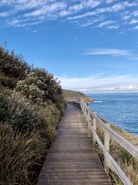 Boardwalk leading towards sea against sky