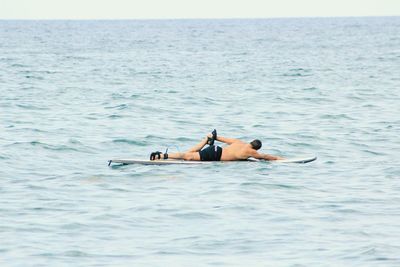 Low section of man lying in sea