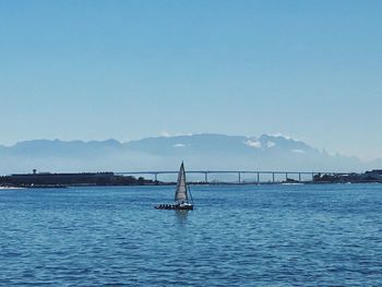 Sailboat sailing in sea against clear blue sky