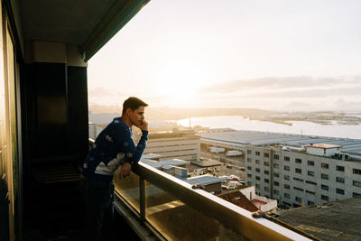 Side view of young man standing against sky