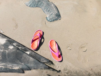 Directly above shot of flip-flops on wet sand at beach