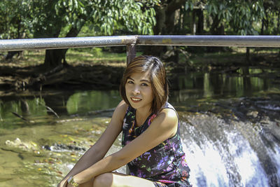 Portrait of beautiful woman sitting with stream in background