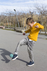 Rear view of boy with umbrella on road