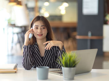 Young businesswoman talking on phone while sitting in office