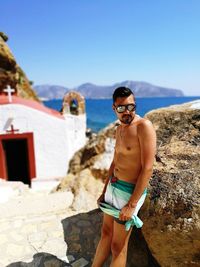 Man wearing sunglasses standing on mountain against clear blue sky