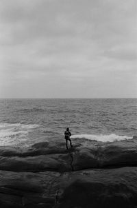 Rear view of man standing at beach against sky