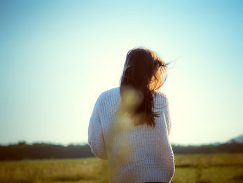 Rear view of woman standing on land against sky