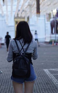 Rear view of woman with backpack walking in city