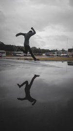 Man jumping in water against sky