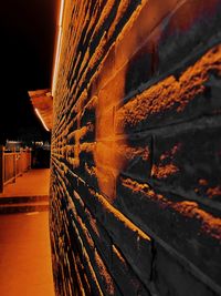 Stack of illuminated building by wall at night