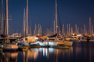 Sailboats moored in harbor at night