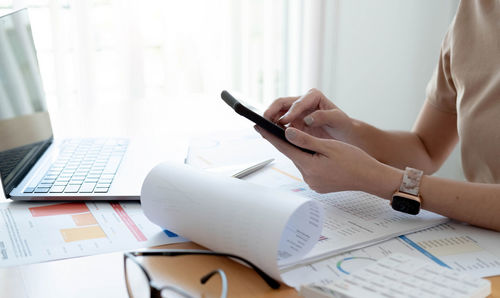 Midsection of woman using mobile phone on table