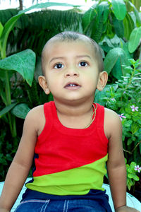 Two years old wearing colorful vest, portrait of asian baby boy playing in home garden