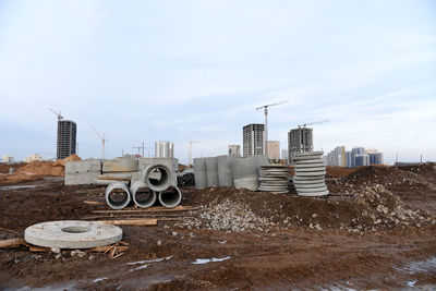 Construction site on field by buildings against sky