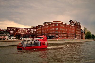 Boat in river against buildings in city