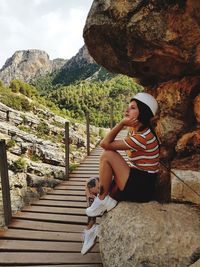 Woman with arms raised on rock against mountains