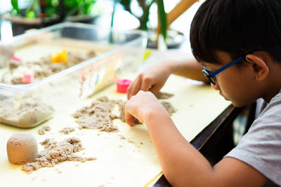 Side view of boy playing with sand