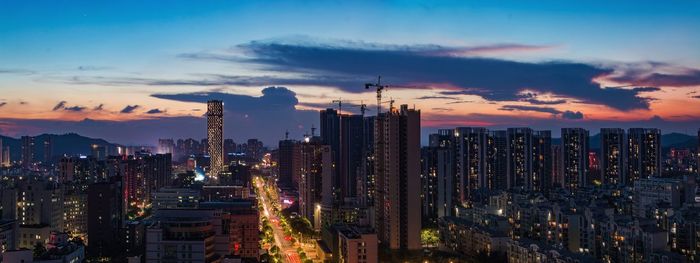 Panoramic view of illuminated city buildings against sky during sunset