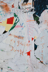Close-up of torn poster with text on wall