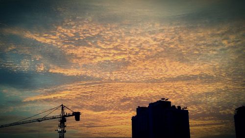 Low angle view of silhouette building against cloudy sky