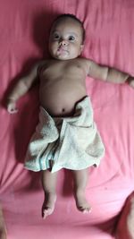 Portrait of cute baby girl lying on bed