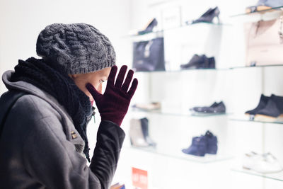 Side view of woman wearing knit hat standing in store