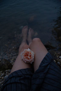 Low section of woman with flower at lake