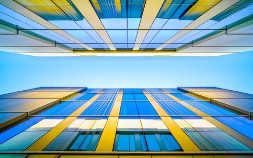 Directly below shot of modern buildings against clear blue sky