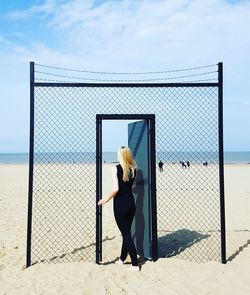 Full length of woman walking on doorway at beach against sky