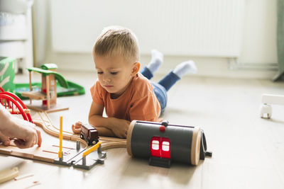 Son lying on floor and looking at toy train at home