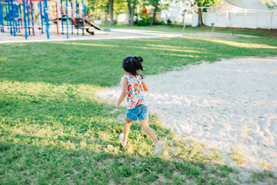 Rear view of boy running on field