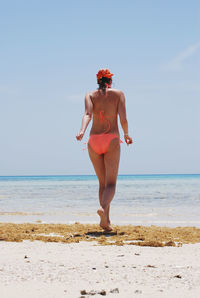 Full length of woman in bikini walking at beach