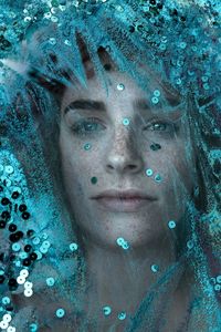 Close-up of woman behind glass decorated with sequins