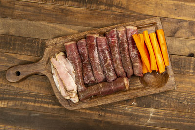 Beef roll raw to prepare with bacon and carrots on a kitchen board