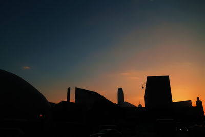 Silhouette buildings against sky at sunset