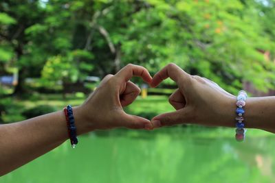 Cropped image of hands making heart shape at park