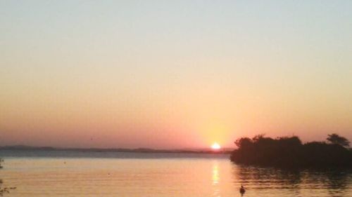 Scenic view of lake against clear sky during sunset