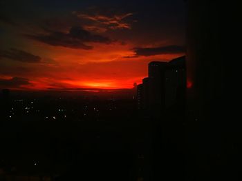 Silhouette buildings against dramatic sky during sunset