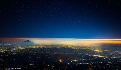 Aerial view of illuminated city against sky at night