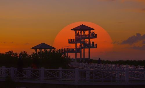 Silhouette cranes against orange sky