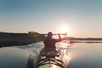 Man on boat in lake against sky during sunset