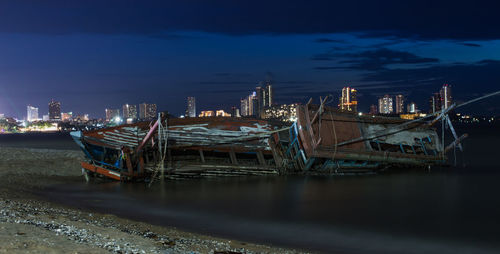 Fishing boats moored in sea against sky at night