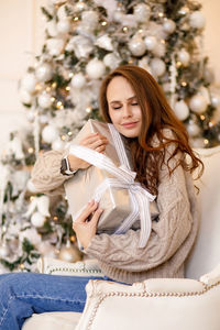 Young woman in a sweater and jeans on the background of christmas decorations