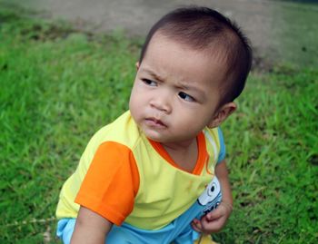 Cute boy looking away while crouching on field