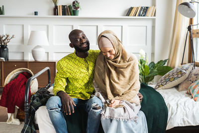 Smiling couple sitting on bed at home