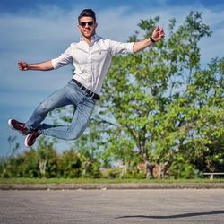 Young man jumping in city against sky