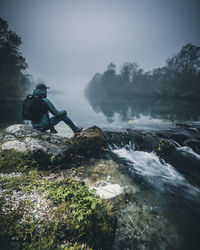 Man standing on rock against waterfall