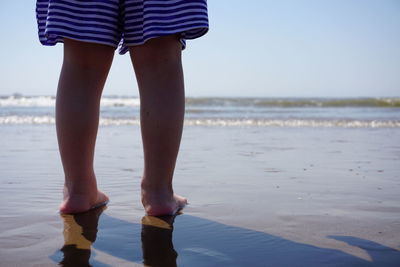 Low section of woman standing at beach