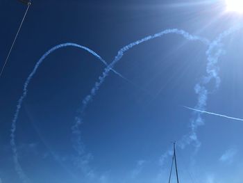 Low angle view of vapor trails against blue sky
